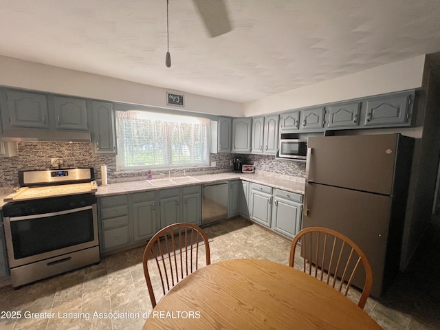 709 N Mead St, Saint Johns, MI 48879 - kitchen with appliances with stainless steel finishes, gray cabinetry, tasteful backsplash, and light countertops