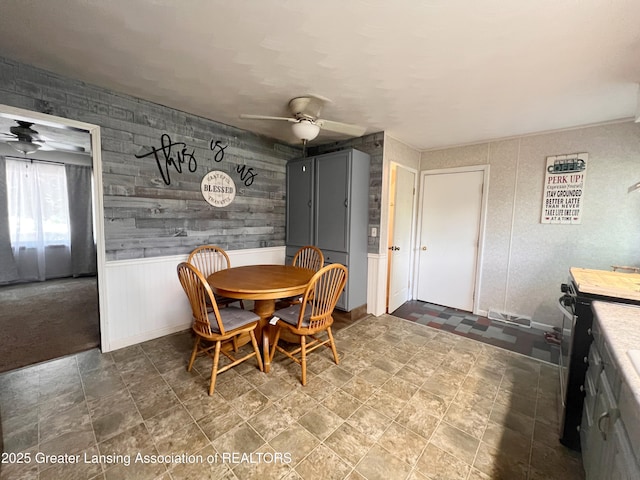 709 N Mead St, Saint Johns, MI 48879 - dining space featuring a ceiling fan, a wainscoted wall, and stone finish flooring