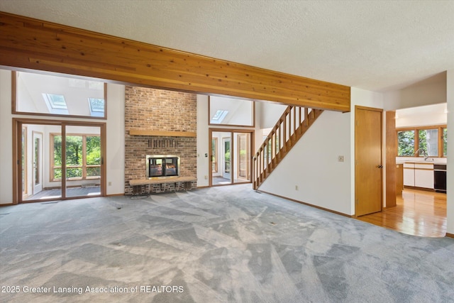 2575 Capeside Dr, Okemos, MI 48864 - unfurnished living room with carpet flooring, stairs, a textured ceiling, and a fireplace