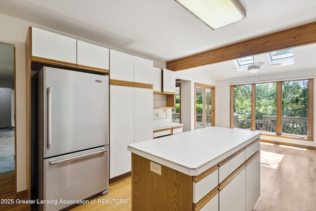 2575 Capeside Dr, Okemos, MI 48864 - kitchen with freestanding refrigerator, a skylight, light wood-type flooring, white cabinetry, and a center island