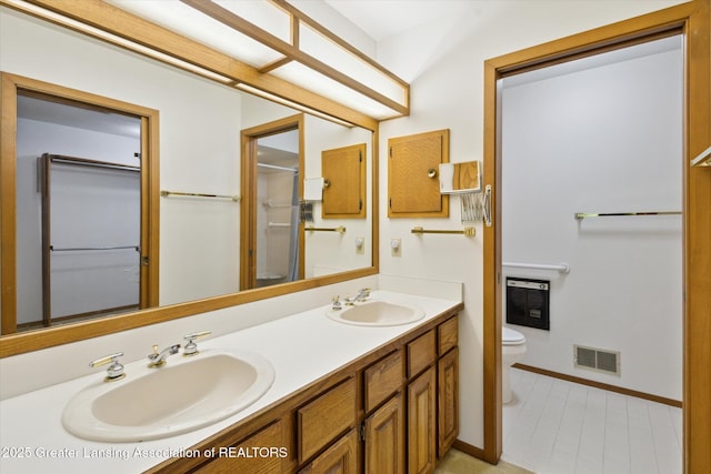 2575 Capeside Dr, Okemos, MI 48864 - bathroom featuring double vanity, heating unit, and a shower with shower door