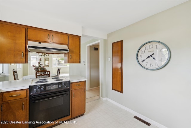 873 Union Ave, Owosso, MI 48867 - kitchen featuring range with electric cooktop, under cabinet range hood, brown cabinets, and light countertops
