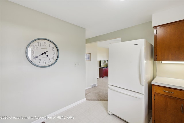 873 Union Ave, Owosso, MI 48867 - kitchen featuring freestanding refrigerator, light countertops, brown cabinets, and light flooring