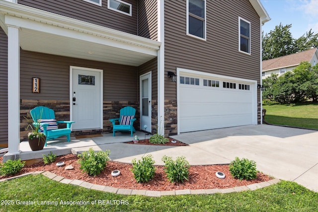 112 E Barber St, Ithaca, MI 48847 - entrance to property featuring a garage, driveway, covered porch, and stone siding