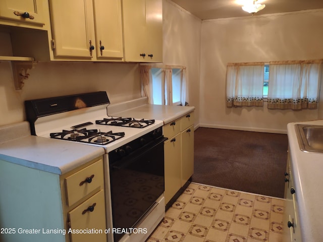 518 Clark St, Eaton Rapids, MI 48827 - kitchen featuring range with gas stovetop, light countertops, light floors, and white cabinetry