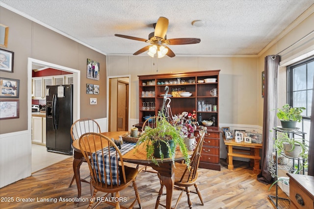 9428 S Wright Rd, Eagle, MI 48822 - dining space featuring crown molding, light wood-style floors, a decorative wall, ceiling fan, and a textured ceiling