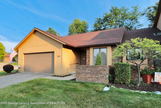 1621 Willow Creek Dr, Lansing, MI 48917 - view of front facade with brick siding, an attached garage, roof with shingles, asphalt driveway, and a front lawn