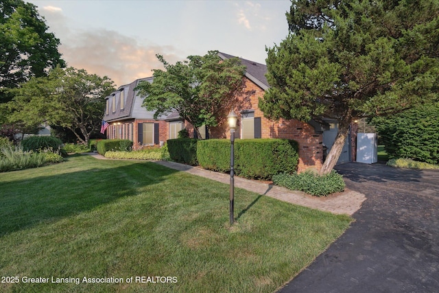 9303 Blueberry Ct, Howell, MI 48843 - obstructed view of property with brick siding, driveway, and a front lawn