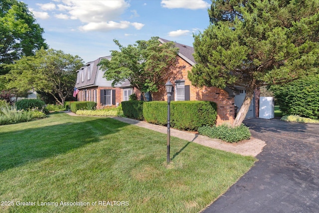 9303 Blueberry Ct, Howell, MI 48843 - view of front of home with brick siding, asphalt driveway, a front lawn, and an attached garage