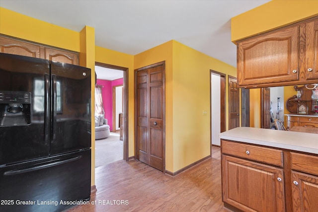 9303 Blueberry Ct, Howell, MI 48843 - kitchen featuring black fridge with ice dispenser, light wood-style flooring, light countertops, and brown cabinetry