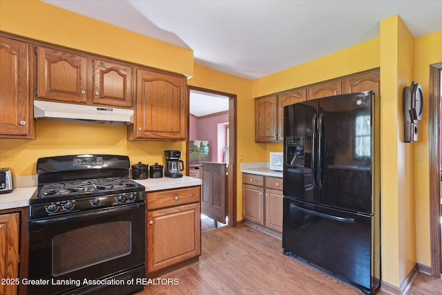 9303 Blueberry Ct, Howell, MI 48843 - kitchen featuring black appliances, light wood-style floors, light countertops, and under cabinet range hood