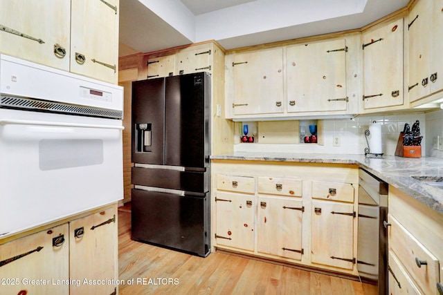 2315 Hamilton Rd, Okemos, MI 48864 - kitchen featuring oven, black fridge, light wood-type flooring, light stone countertops, and stainless steel dishwasher