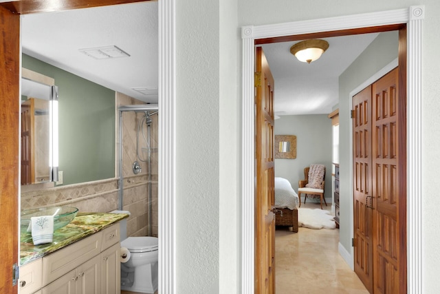 ensuite bathroom featuring ensuite bathroom, vanity, toilet, tile walls, and a stall shower