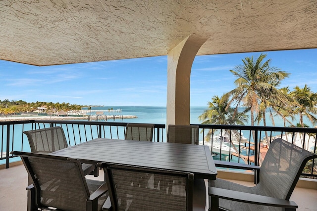 balcony featuring outdoor dining space and a water view