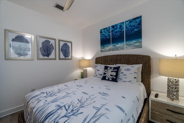 bedroom featuring baseboards, visible vents, and wood finished floors