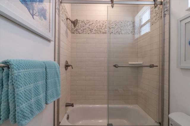 full bathroom featuring toilet and shower / bath combination with glass door
