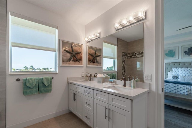full bathroom featuring connected bathroom, a sink, tiled shower, and wood finished floors