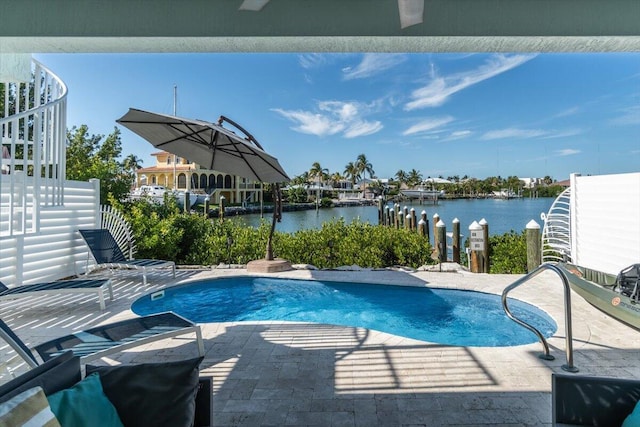 pool with a water view, fence, a dock, and a patio area