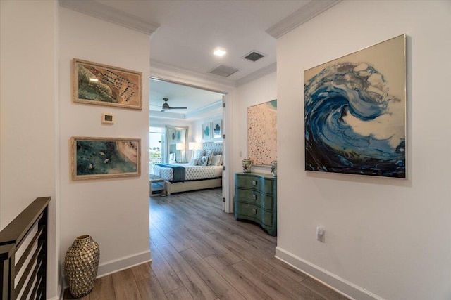 corridor with baseboards, visible vents, crown molding, and wood finished floors