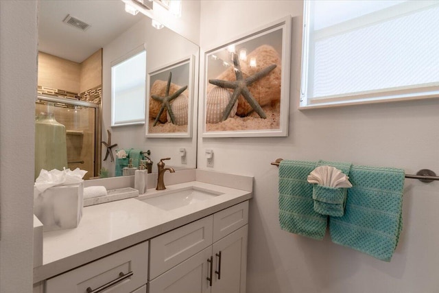 bathroom with vanity, a stall shower, and visible vents