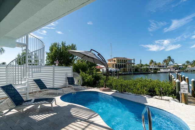pool with a water view, fence, stairway, and a patio area