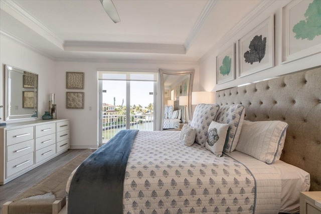 bedroom with ornamental molding, baseboards, a raised ceiling, access to exterior, and wood finished floors
