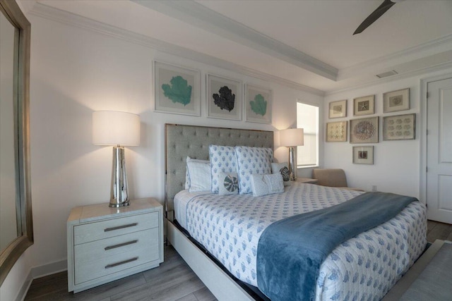 bedroom with a tray ceiling, crown molding, a ceiling fan, dark wood-style floors, and visible vents