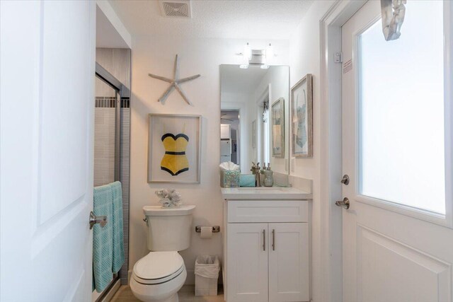 bathroom with toilet, vanity, a textured ceiling, and visible vents