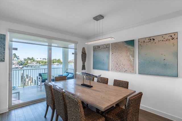 dining area featuring baseboards, a water view, ornamental molding, and wood finished floors