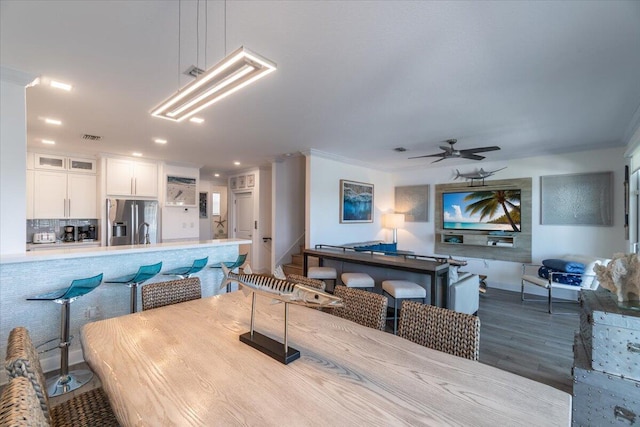 living area with a ceiling fan, visible vents, ornamental molding, and wood finished floors
