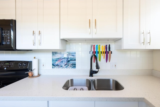 kitchen featuring backsplash, a sink, white cabinetry, light stone countertops, and black appliances