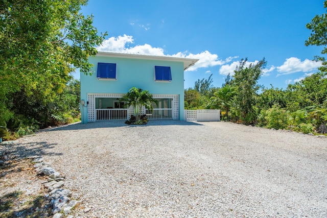view of front of property featuring gravel driveway, stucco siding, and fence