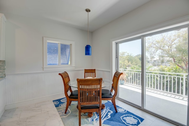 dining space featuring a wainscoted wall and marble finish floor