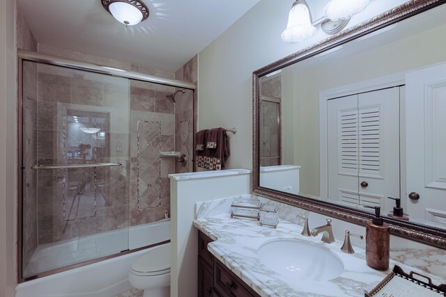 full bath featuring vanity, toilet, and shower / bath combination with glass door