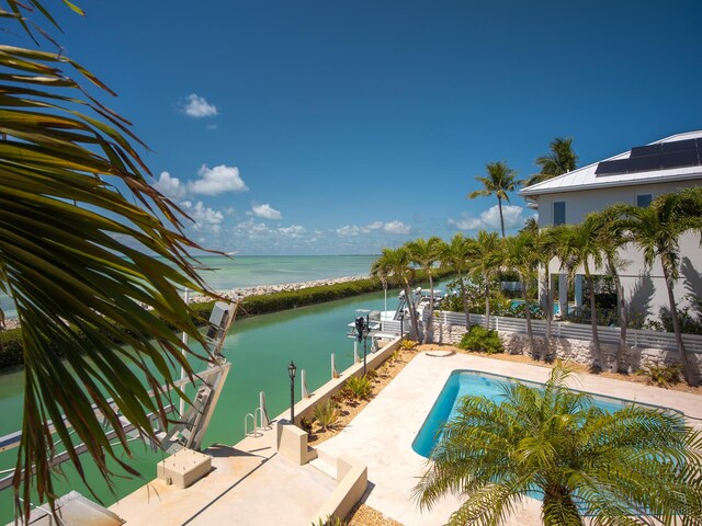 view of swimming pool featuring fence, a water view, a boat dock, and a fenced in pool