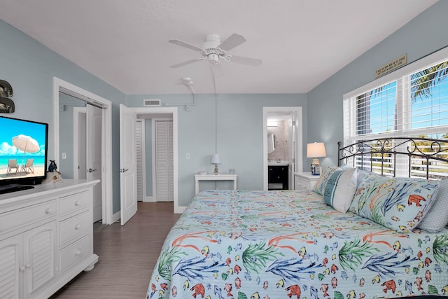 bedroom with baseboards, visible vents, a ceiling fan, wood finished floors, and ensuite bathroom