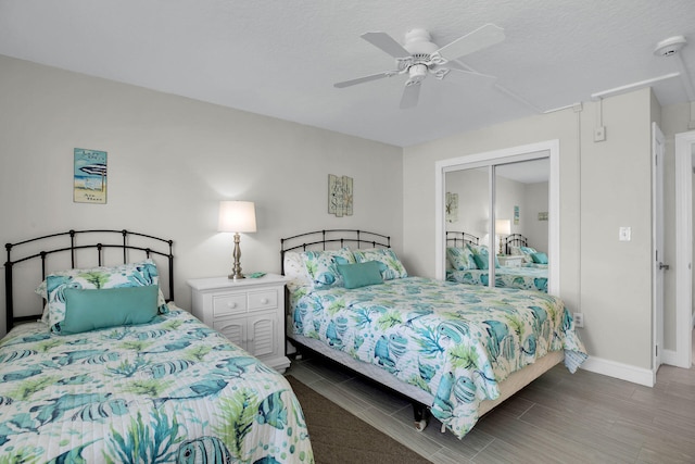 bedroom featuring baseboards, a ceiling fan, wood finished floors, a textured ceiling, and a closet