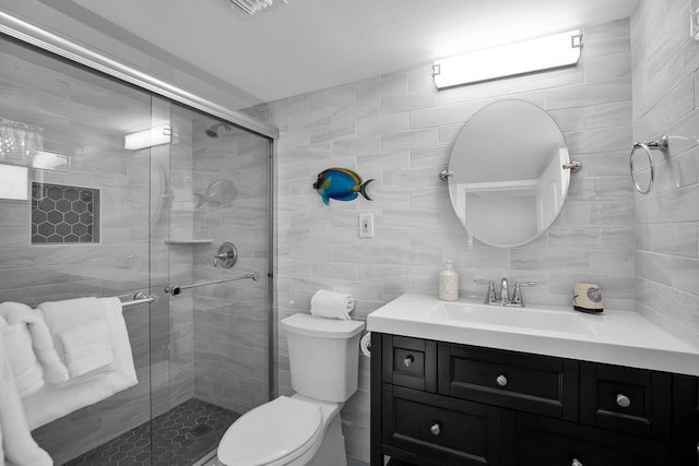 bathroom with a stall shower, tile walls, toilet, and vanity