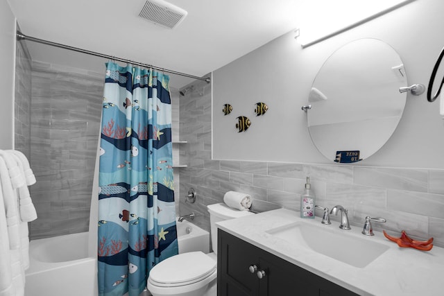 bathroom with visible vents, toilet, shower / bath combo with shower curtain, vanity, and tile walls