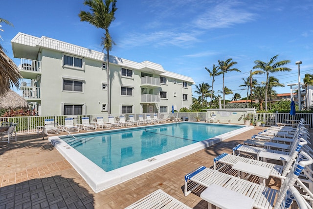 community pool with a patio area and fence