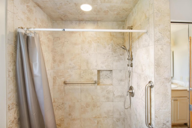 bathroom with tiled shower and vanity