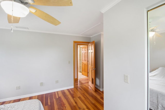 bedroom with wood finished floors, a ceiling fan, baseboards, ornamental molding, and a closet