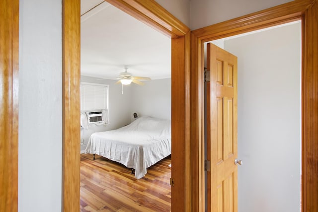 bedroom with a ceiling fan, cooling unit, and wood finished floors