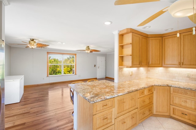 kitchen featuring ceiling fan, open shelves, backsplash, and light stone countertops