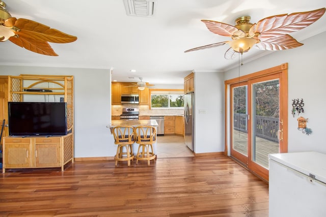 interior space with crown molding, visible vents, light wood-style floors, ceiling fan, and baseboards