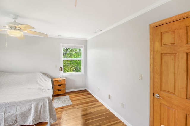 bedroom featuring visible vents, ornamental molding, light wood-style floors, ceiling fan, and baseboards