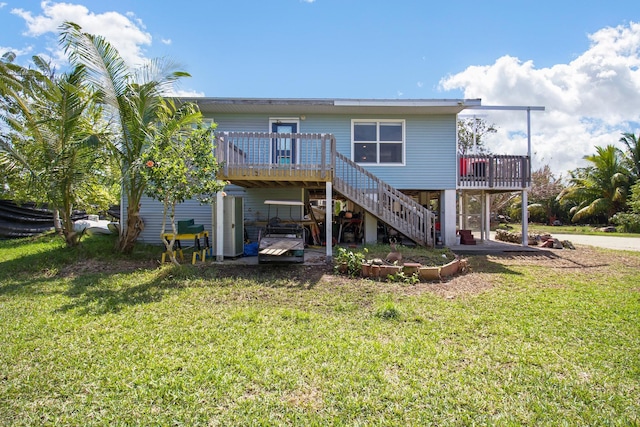 back of house featuring stairway, a lawn, and a wooden deck