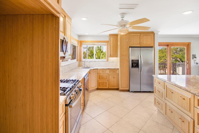 kitchen with light stone counters, stainless steel appliances, light brown cabinetry, a healthy amount of sunlight, and a sink