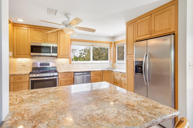 kitchen with visible vents, decorative backsplash, appliances with stainless steel finishes, a sink, and light stone countertops