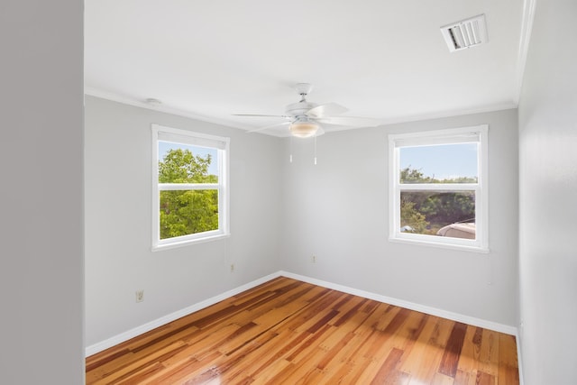 empty room featuring a ceiling fan, visible vents, light wood-style flooring, and baseboards